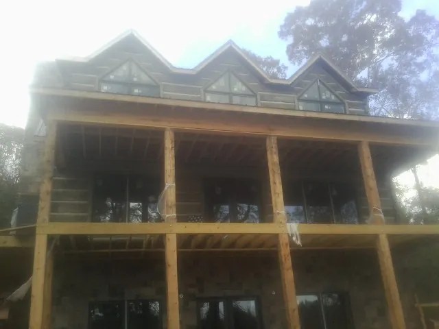 Dormers and porch framing on a large log home under construction — Roof Coating work by our crew in Timberlake