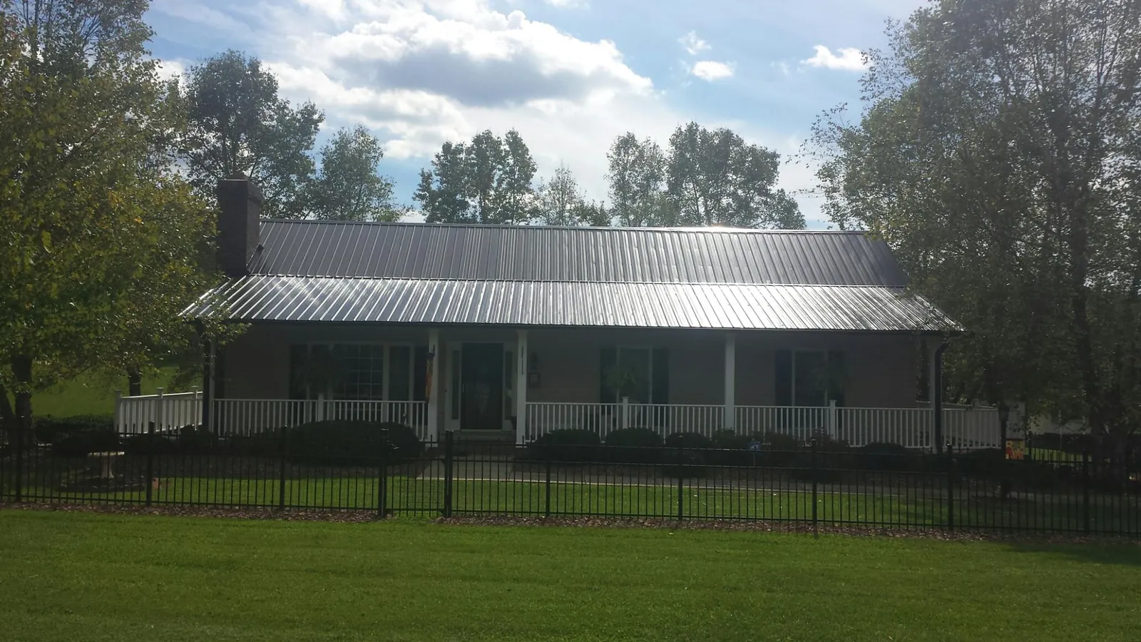 Gray metal roof on a brick ranch with a full width front porch — Gutter Guard Installation work by our crew in Timberlake